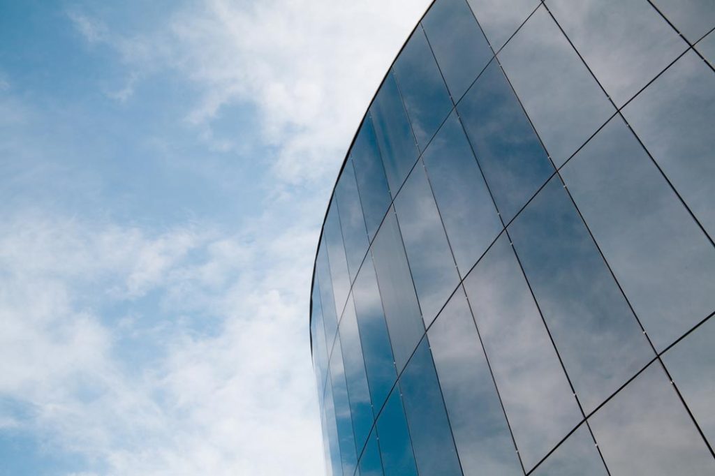 Glass building reflecting clouds and sky