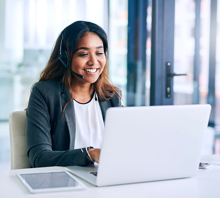 young woman using a headset and laptop in a modern office