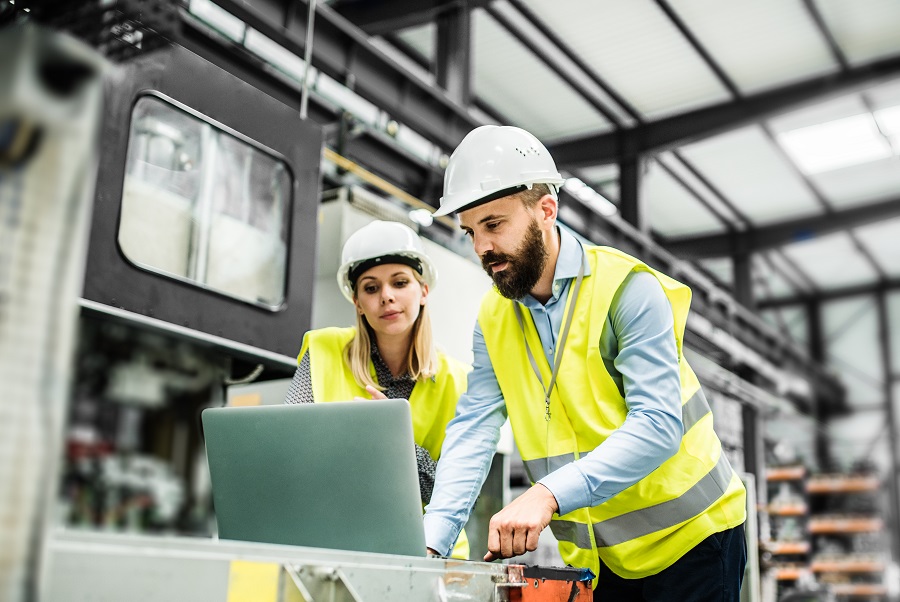 Two people working on laptop in industrial setting