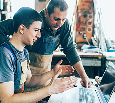 Young man in virtual meeting with older man looking on