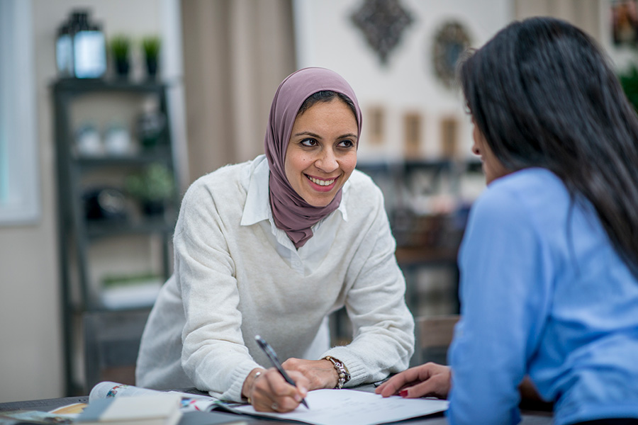 Woman wearing headscarf in discussion with another woman