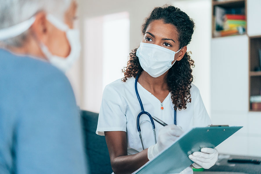 Masked doctor confers with patient