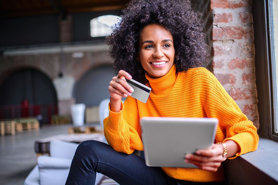 Woman holding credit card and tablet