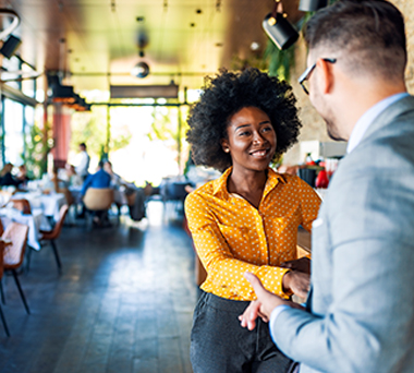 Woman shaking man's hand inside restaurant