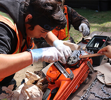Person fixing chainsaw with assitance