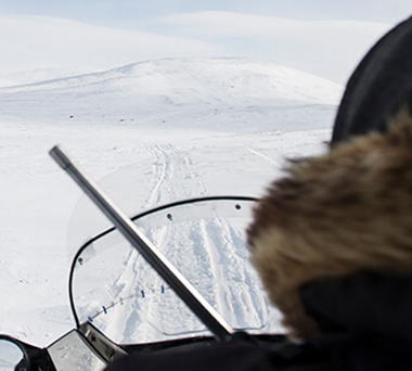 Person driving skidoo across wintery tundra