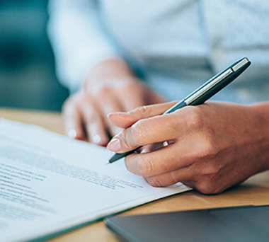 Hand holding pen about to sign document