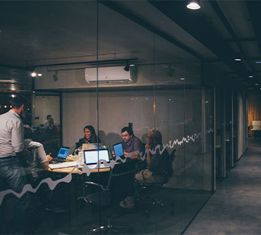 Boardroom full of coworkers collaborating over laptops