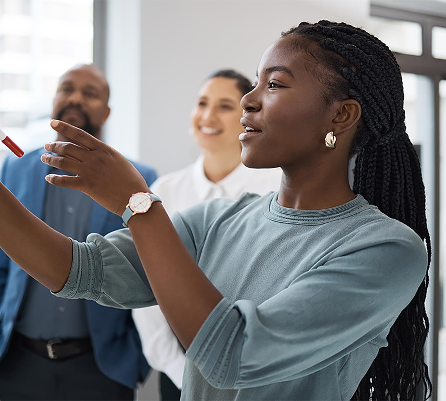 Young businesswoman using a whiteboard while brainstorming with her colleagues in an office