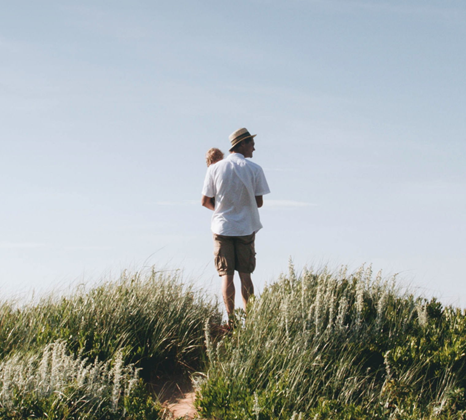 Man holding child on sandy coast.