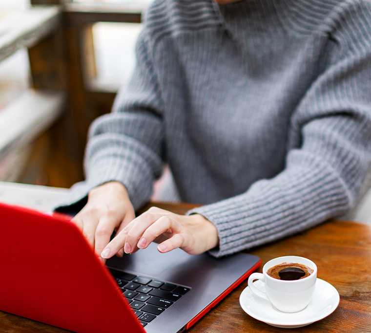 someone typing on a laptop at a cafe