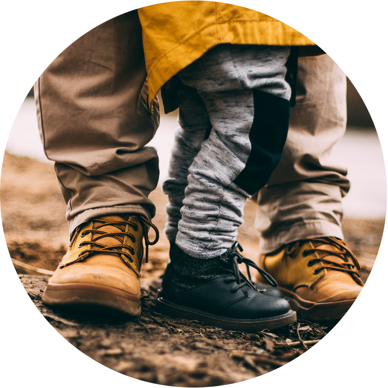 low shot of a son standing in between a father's feet