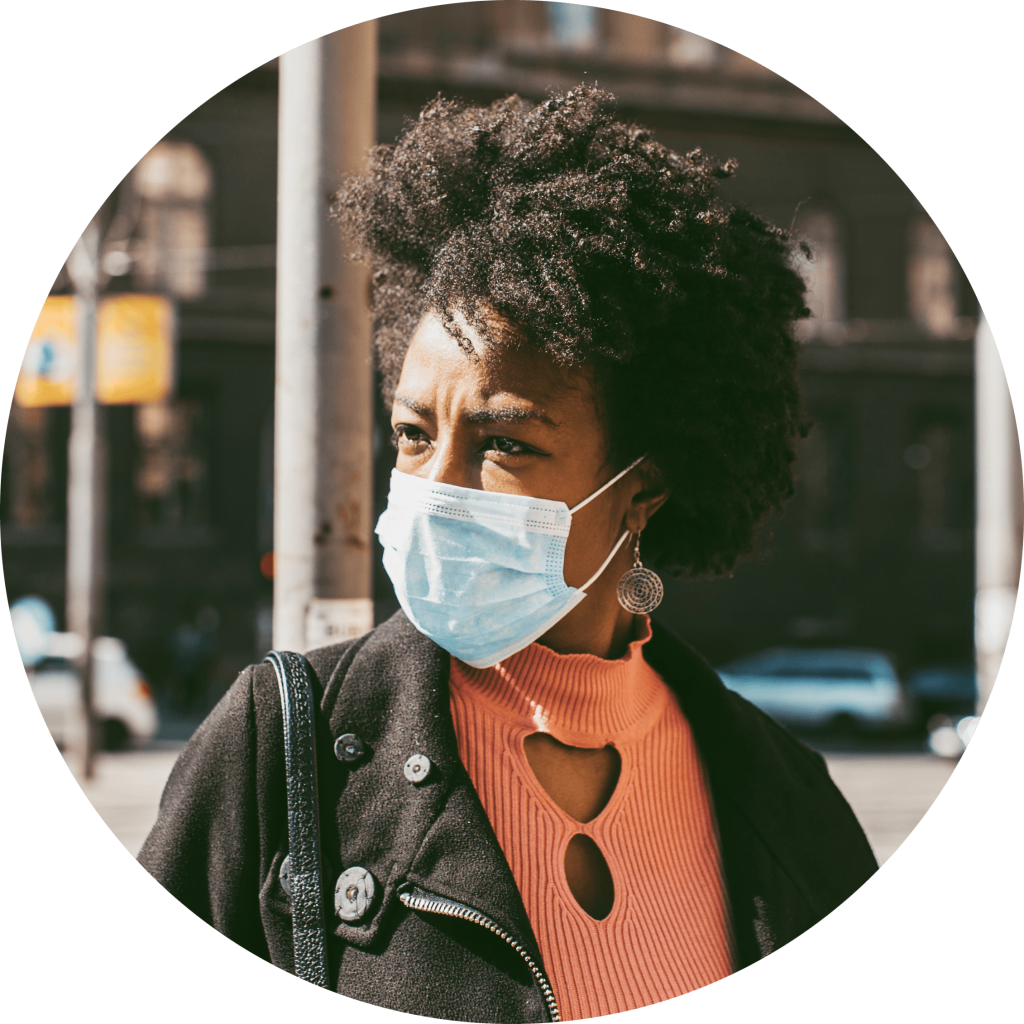 Portrait shot of a person in the streets staring into the distance wearing a mask