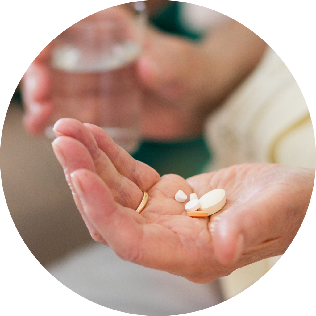 Close up of elderly person's hand with many different sized prescription pills in their hand.