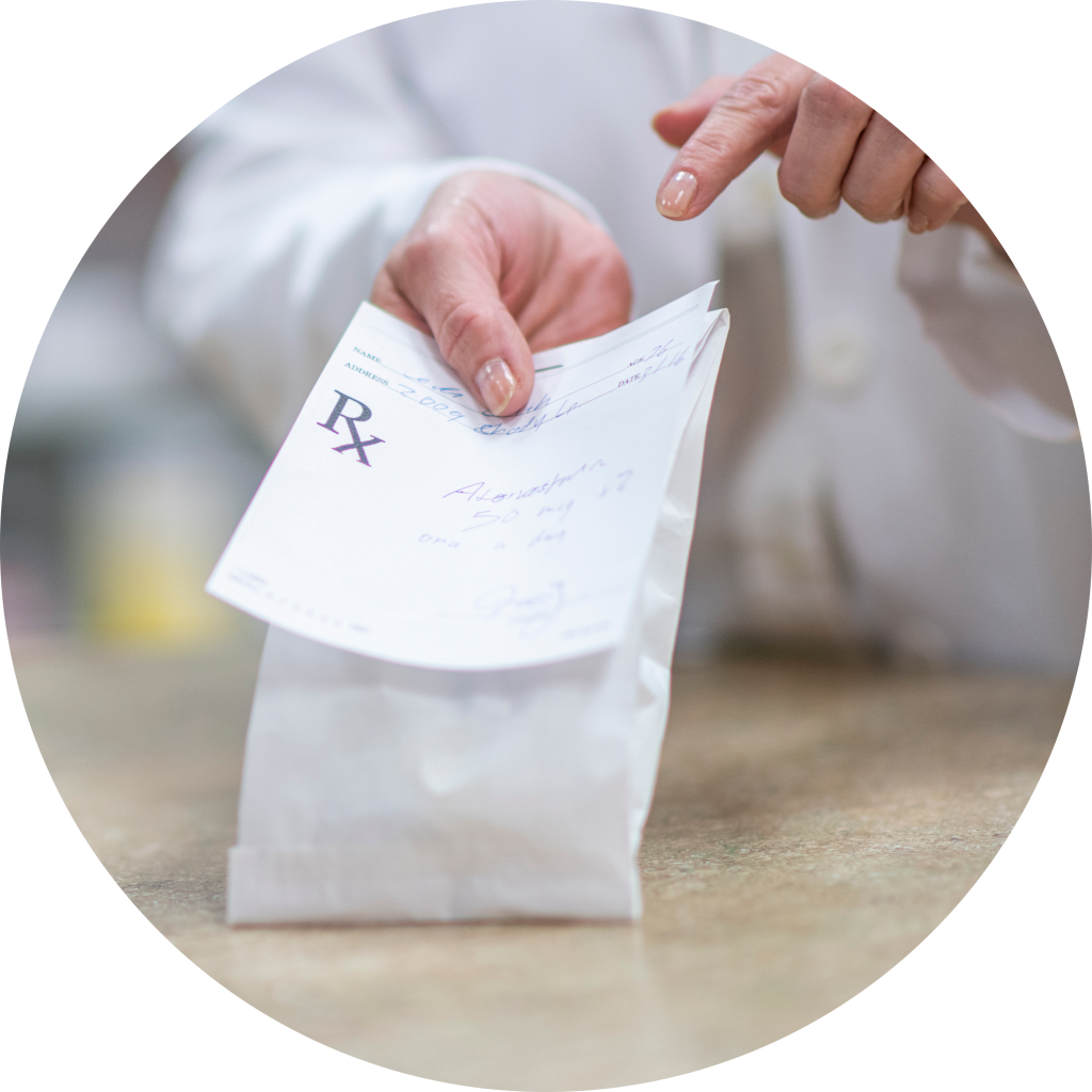 Pharmacist handing over prescription on counter pointing at the label