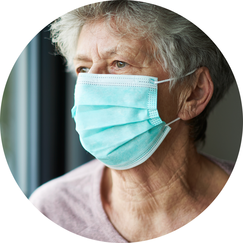 Person staring out the window with a mask on