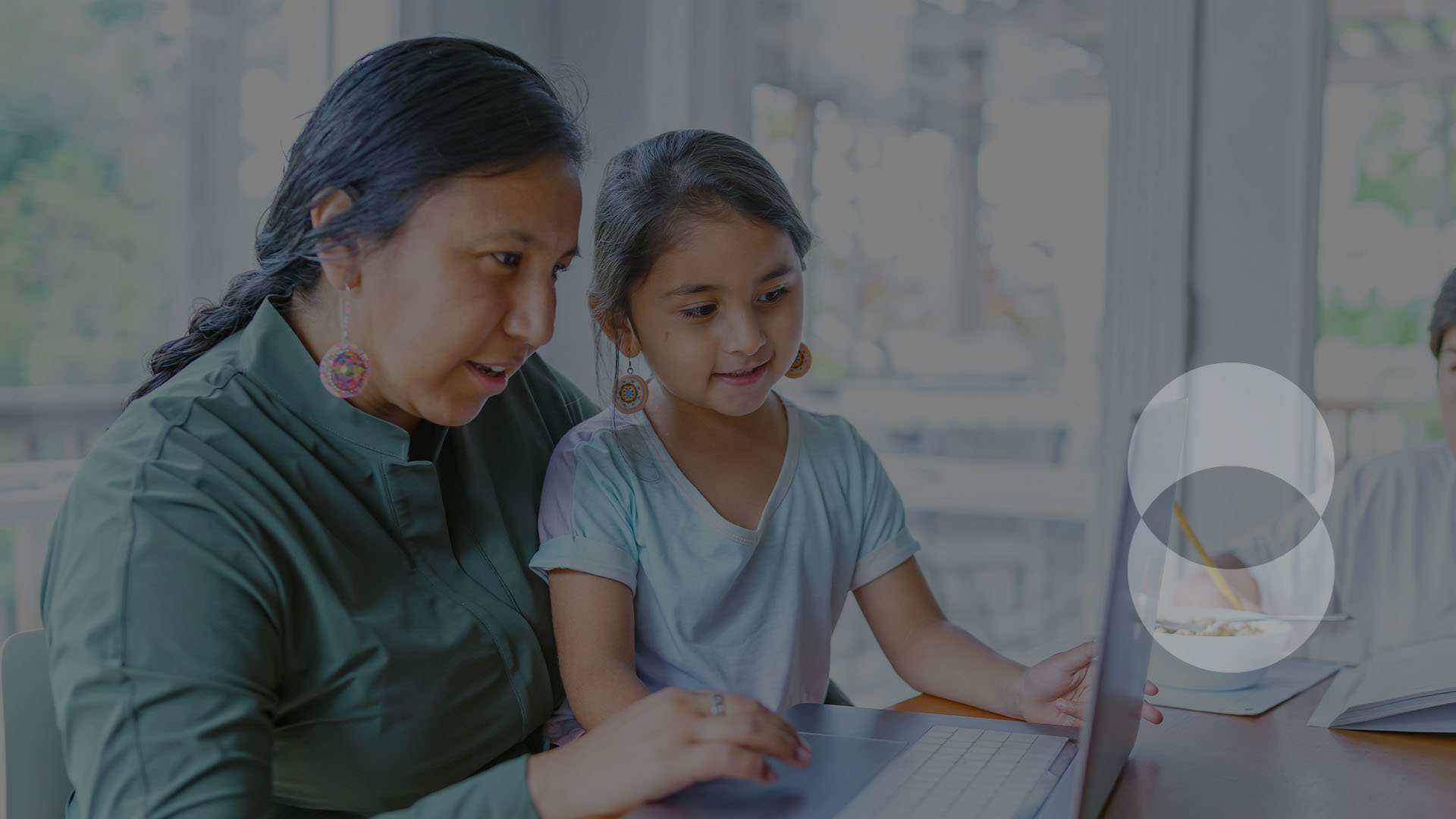 indigenous parent with child using a laptop together at a table.