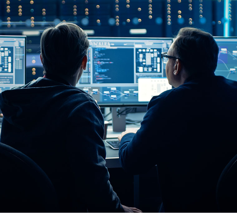 Two Professional IT Programmers Discussing work in front of many computer screens