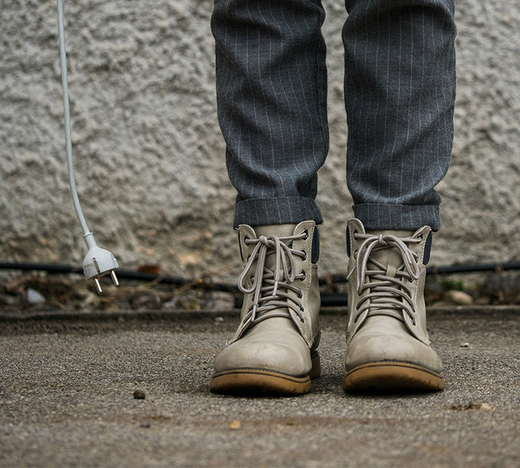 Close up of someone's boots with an unplugged cable.