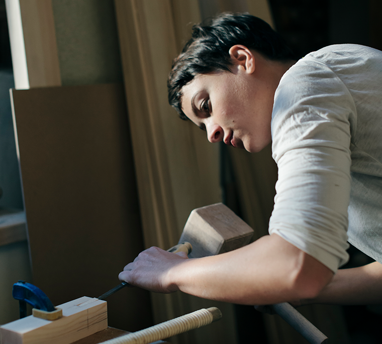 a young woman is woodworking in a workshop