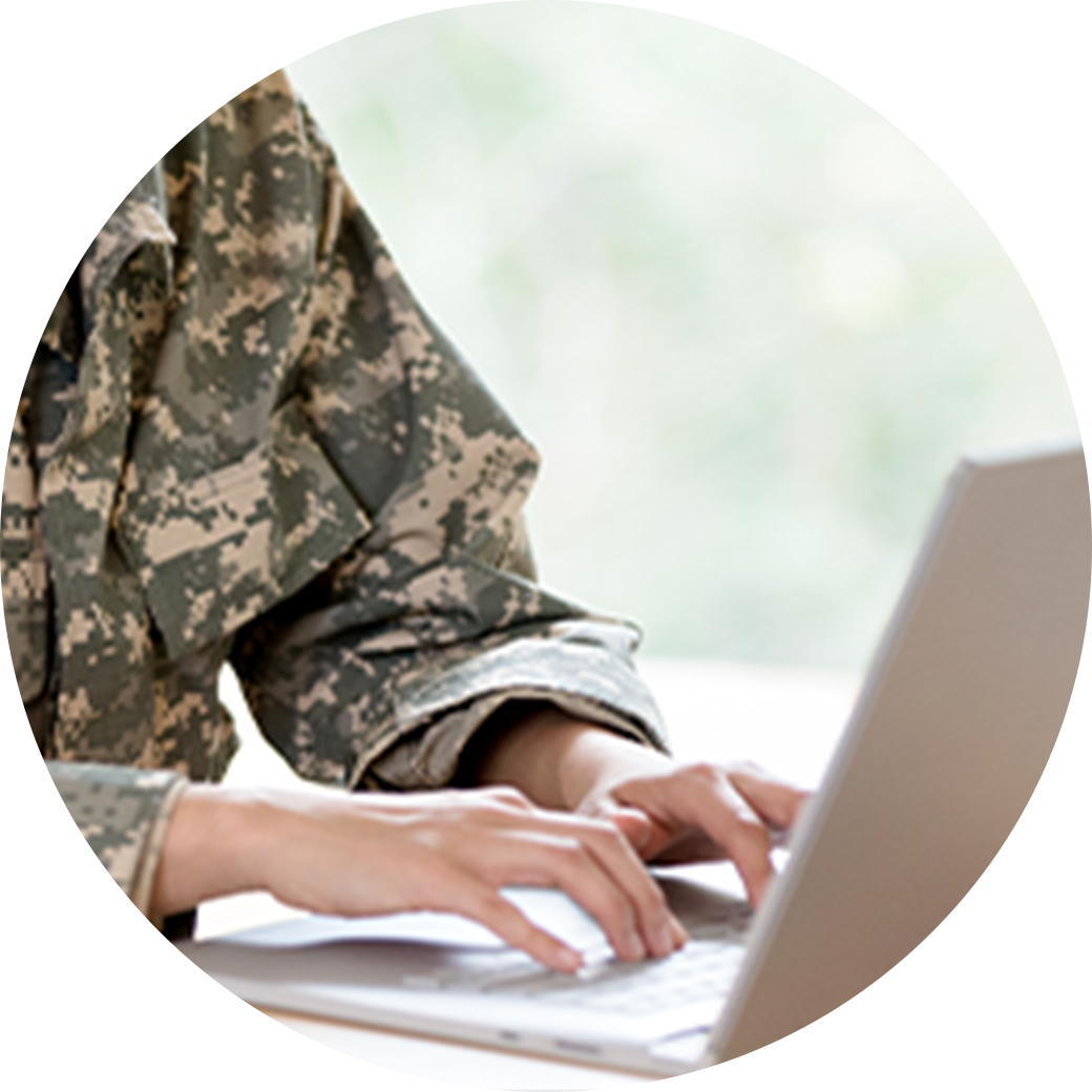 Person typing on a laptop wearing a military jacket