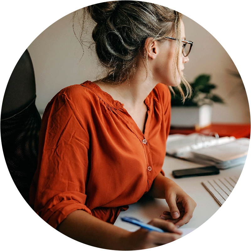Student at a desk holding a pen looking at a computer screen