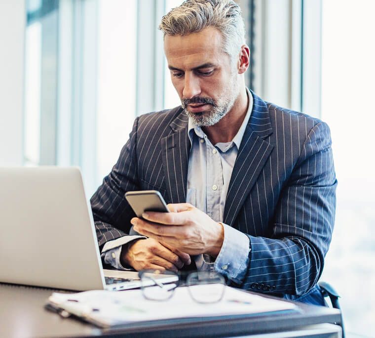 Man reading phone while working at a desk