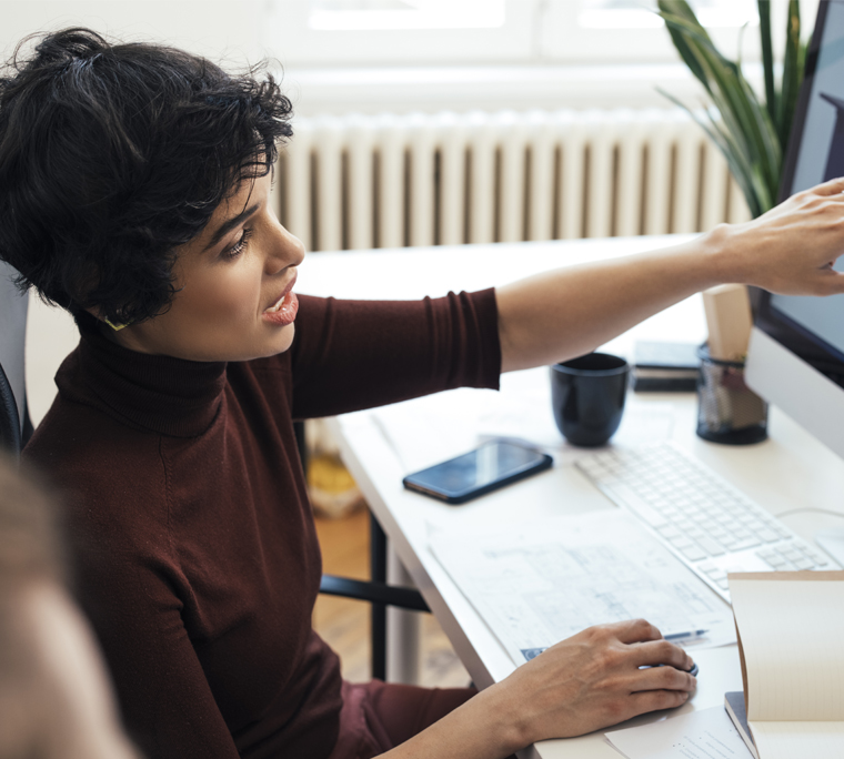 Businesswoman explaining concept on desktop computer to colleague