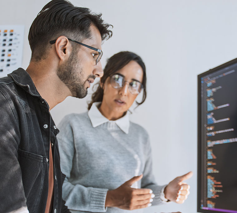coworkers sitting at the computer working through some code