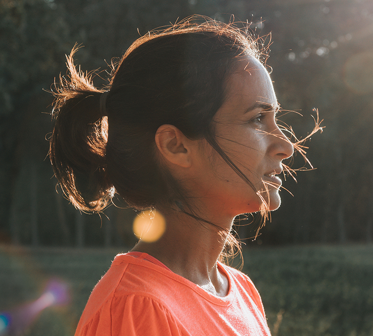 Profile view on woman standing on path in sunny landscape