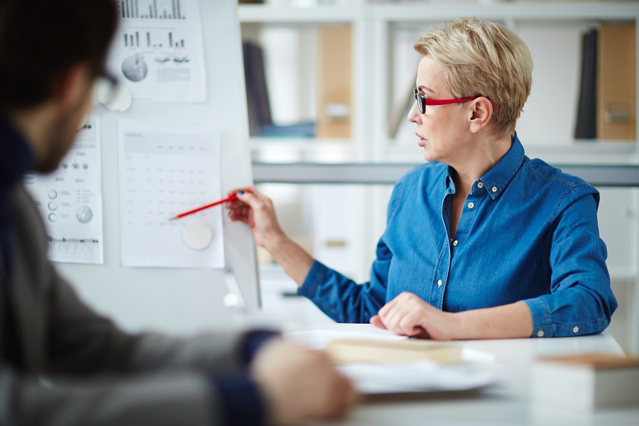 Woman pointing at data on white board during a meeting