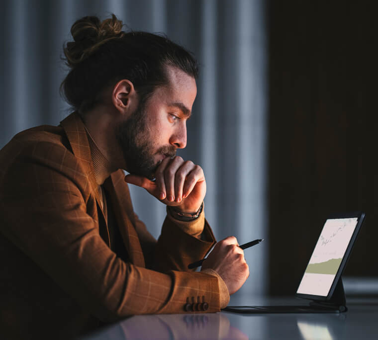 Young man reading on laptop while sitting at a table at night