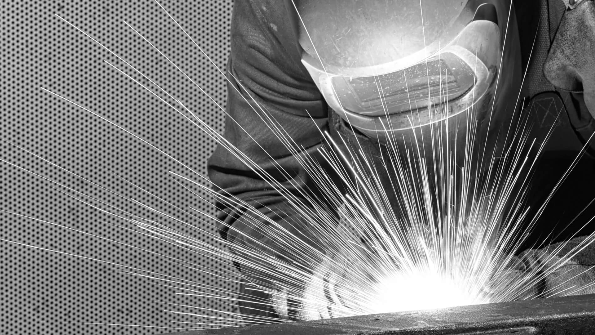 Welder wearing helmet using arc welder