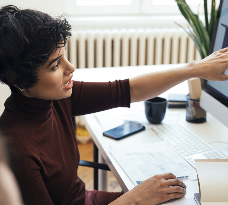 Woman showing work on large monitor with colleague