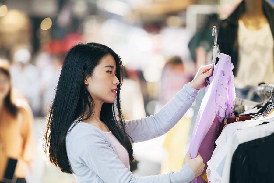 Woman holding up top in clothing store