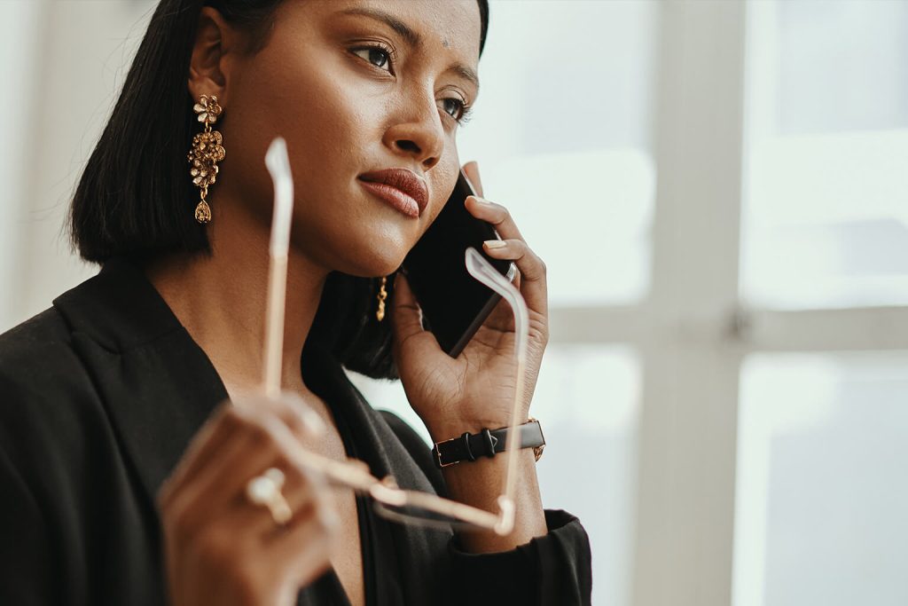 Woman holding glasses while on her phone