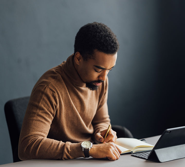man writing notes at his desk