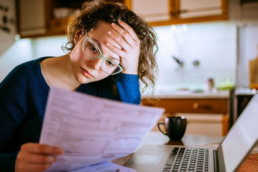 Woman with head in hand reading a bill