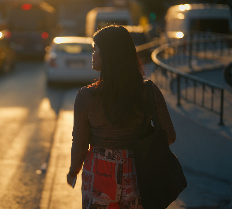 A rear view of a female walking in the street during sunset