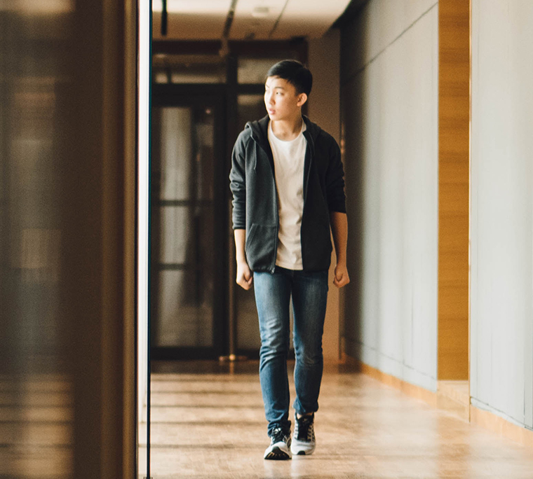 Student walking to class, looking at reflection in window.