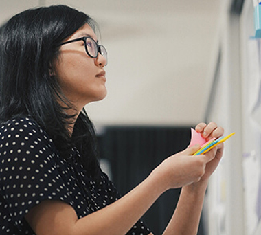 Woman writing post-it note to add to white board