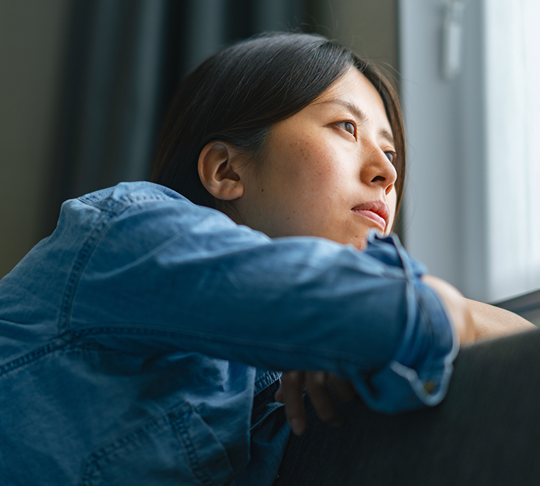 Woman leaning on back of couch looking out a window