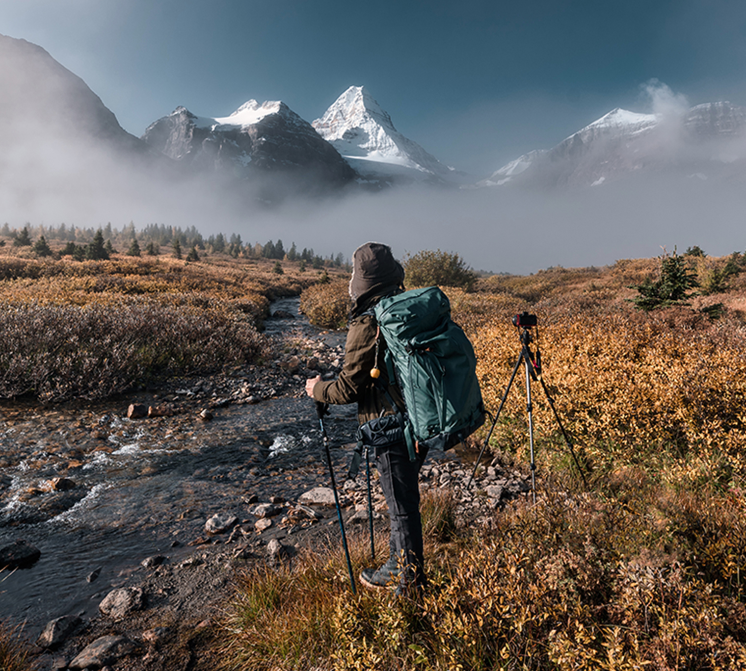 Adventure backpacker with camera standing at mount Assiniboine, Alberta, Canada.