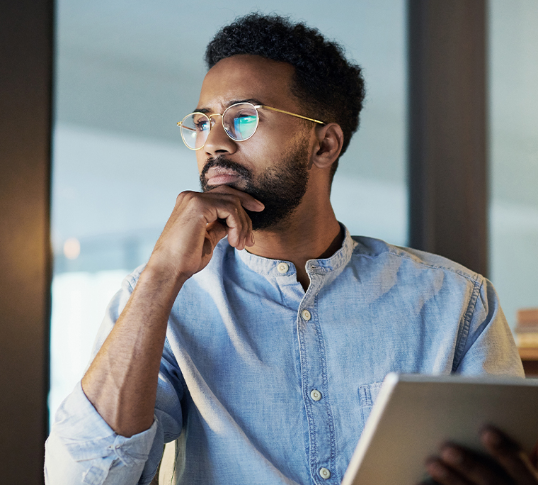 Young African American businessman staring off in thought while holding digital tablet